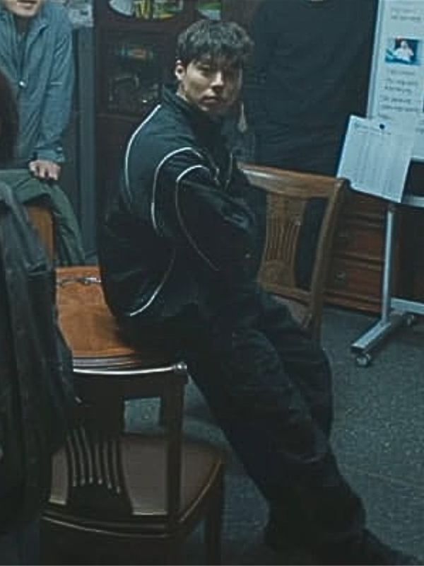 Person sitting on a chair in a room with wooden chairs and a desk.